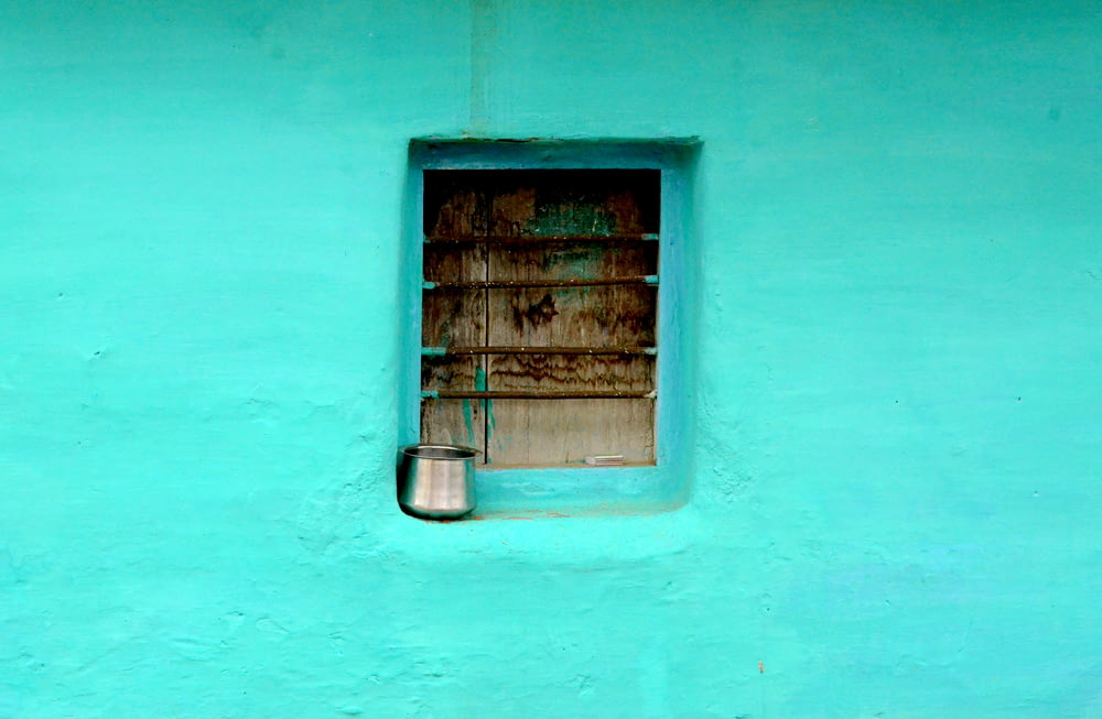 gray steel container on window with teal paint