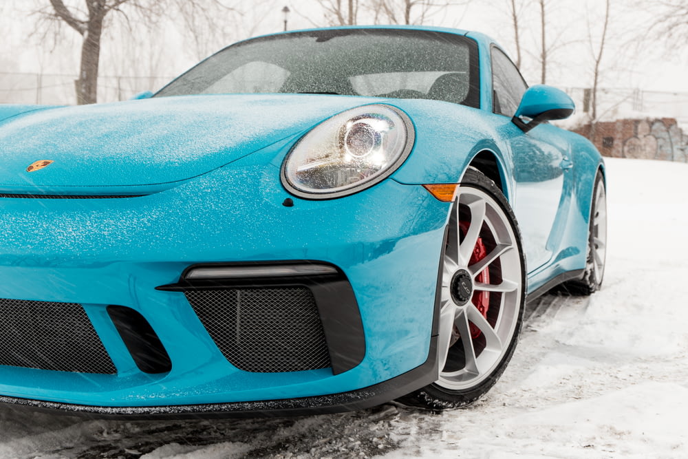 blue Porsche Cayman on snow field near trees