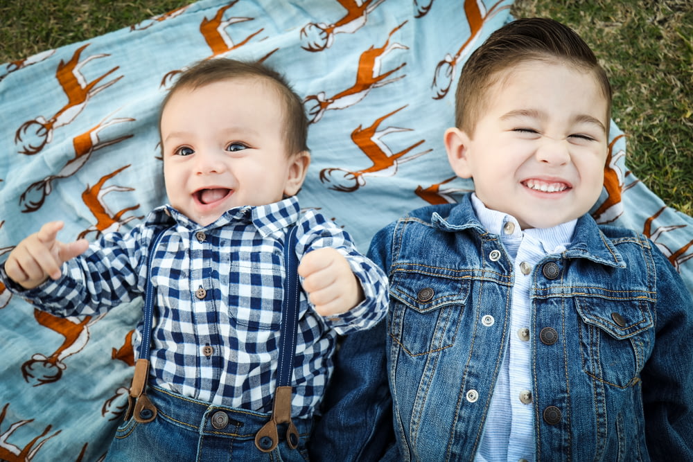 two boys laying on blue textile