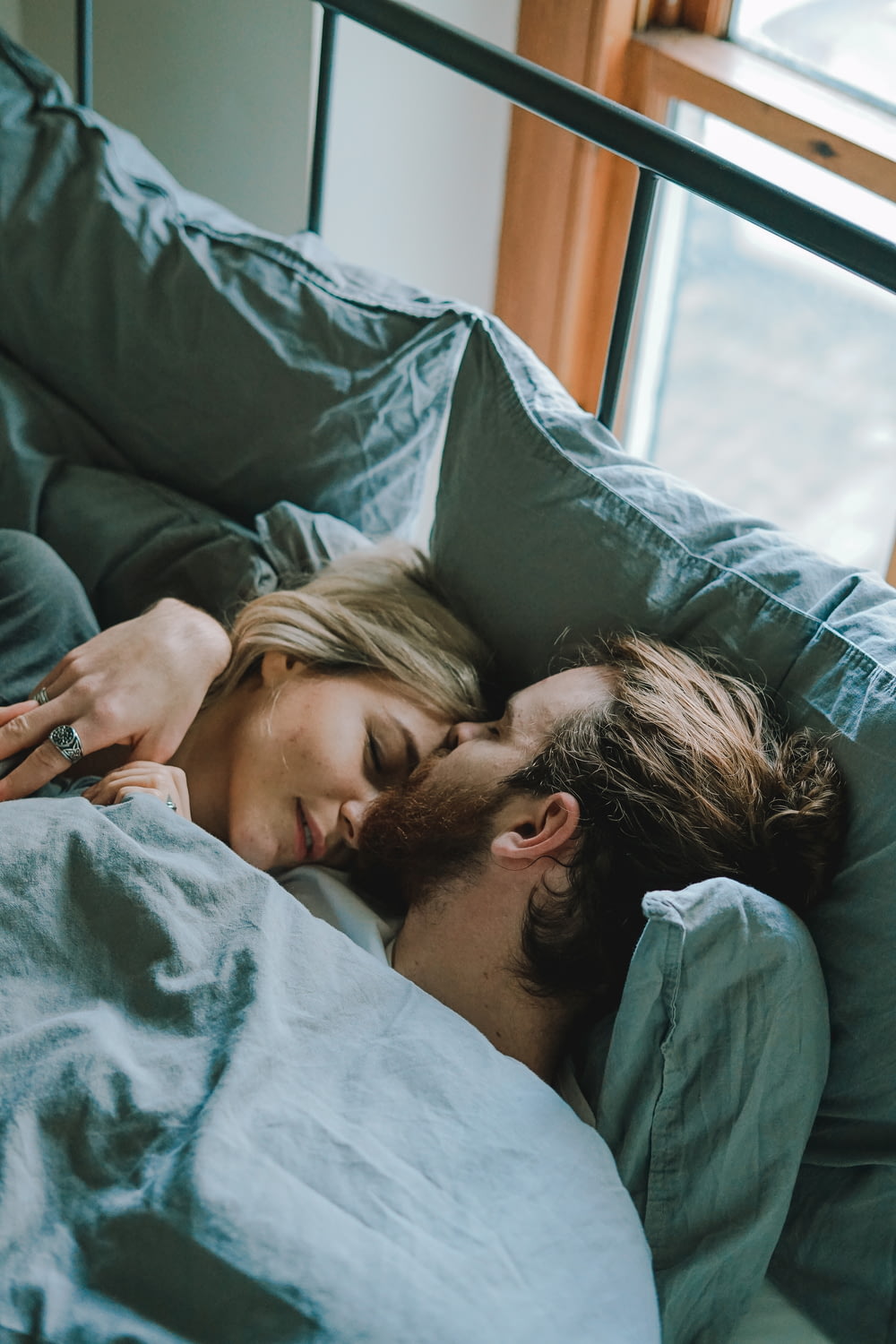 homme embrassant le front d’une femme alors qu’il est allongé sur le lit