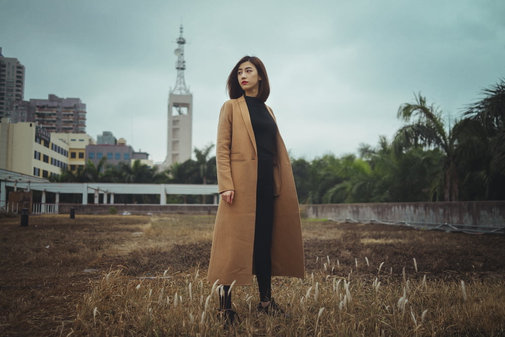 mulher vestindo casaco marrom em pé na grama marrom