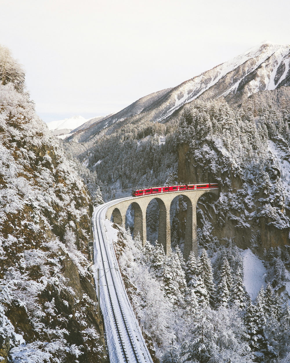Treno rosso in avvicinamento attraverso le montagne