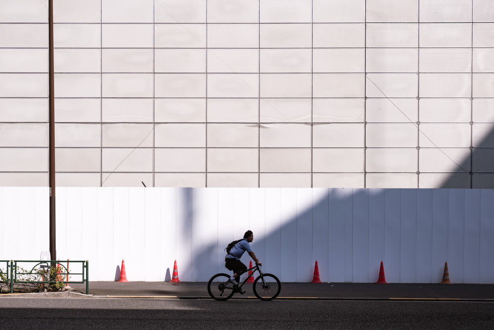 man riding bicycle near white wall during daytime