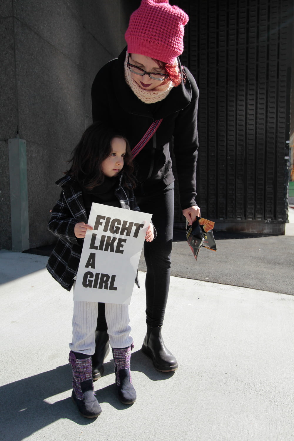 Muchacha sosteniendo la pelea como una muchacha de papel impreso al lado de la mujer sosteniendo el paquete de plástico