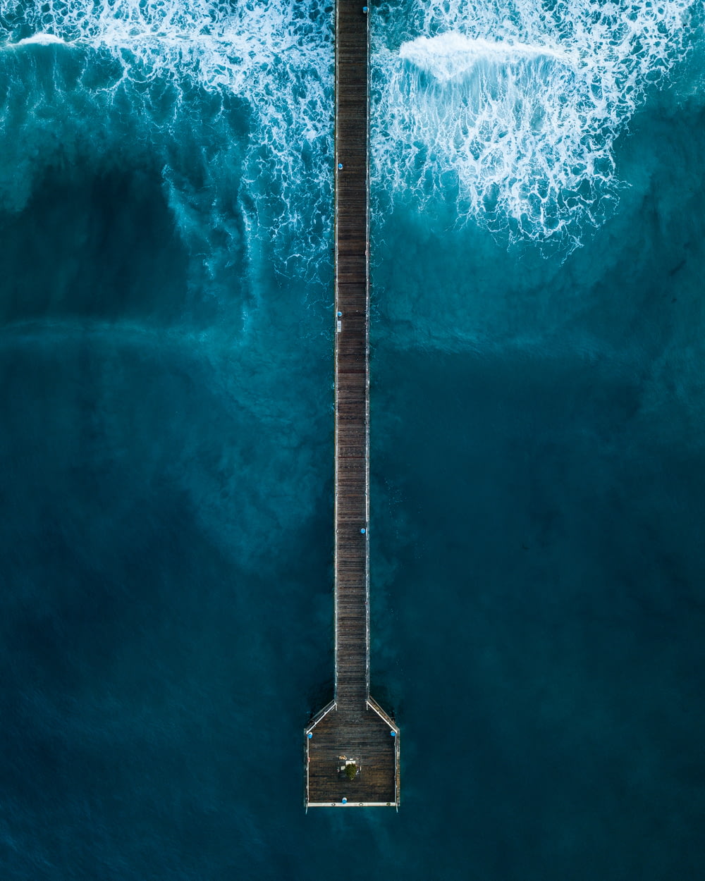 Photographie aérienne d’une personne debout sur le quai au bord de la mer pendant la journée