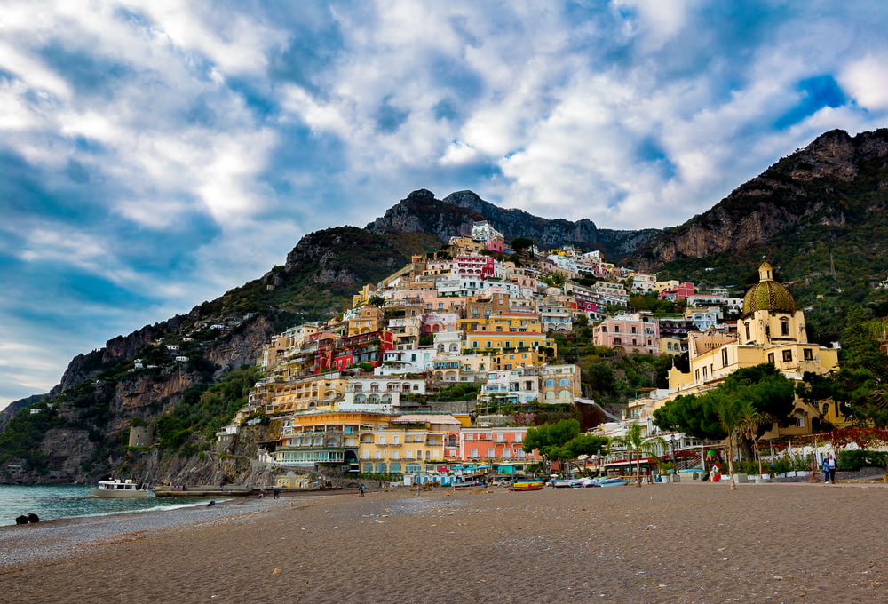 multicolored village on mountain under white and blue skies