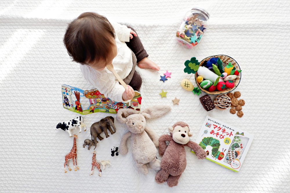 garçon assis sur un tissu blanc entouré de jouets