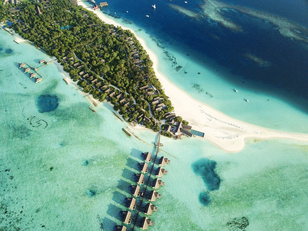 aerial shot of nipa huts on body of water near island