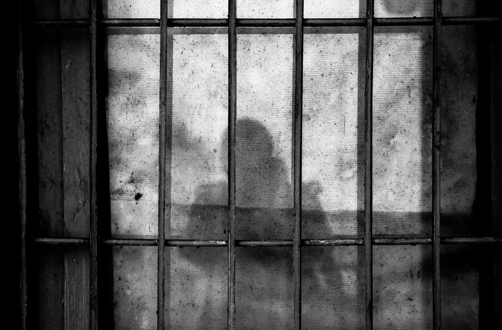 Una sombra de una persona tras las rejas en una celda de la cárcel
