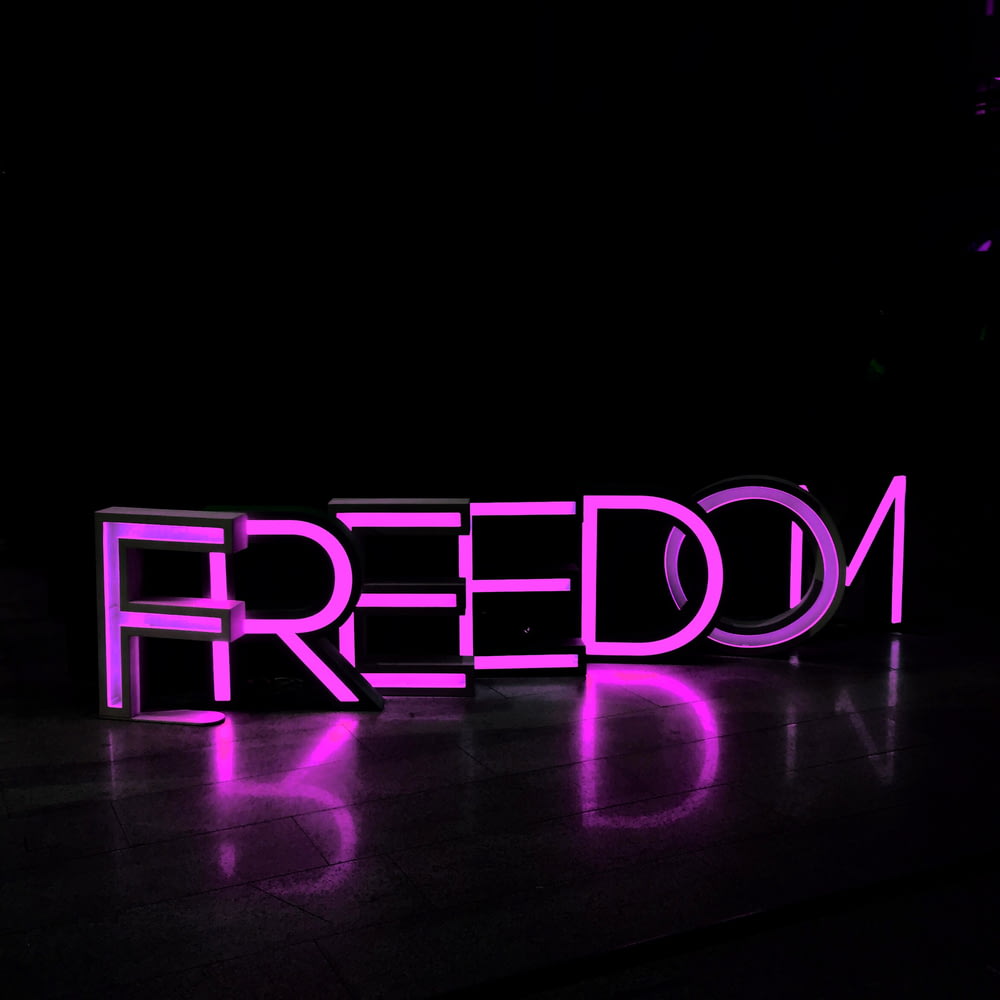lettere autoportanti illuminate Freedom viola su superficie marrone
