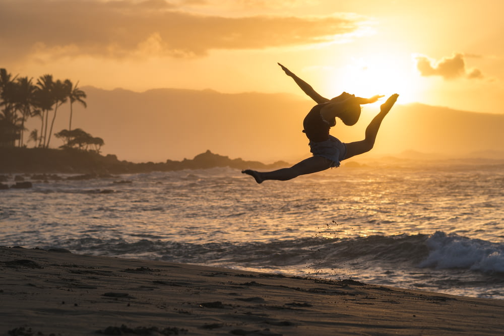 Silhouette einer Frau, die am Meeresufer springt