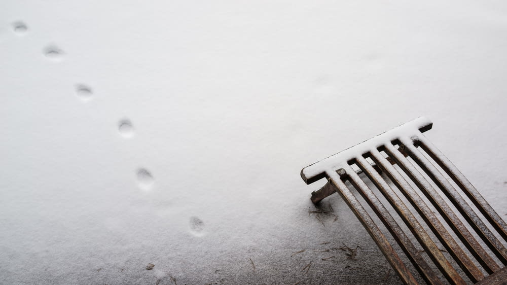 a bench that is covered in snow and footprints