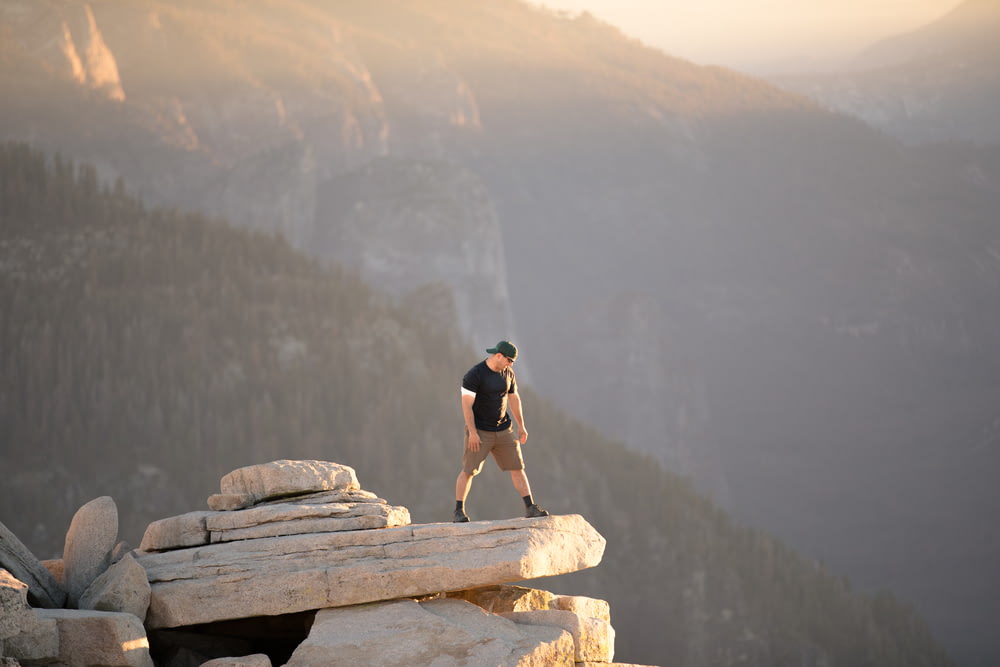 Homem em pé no penhasco da rocha perto da montanha