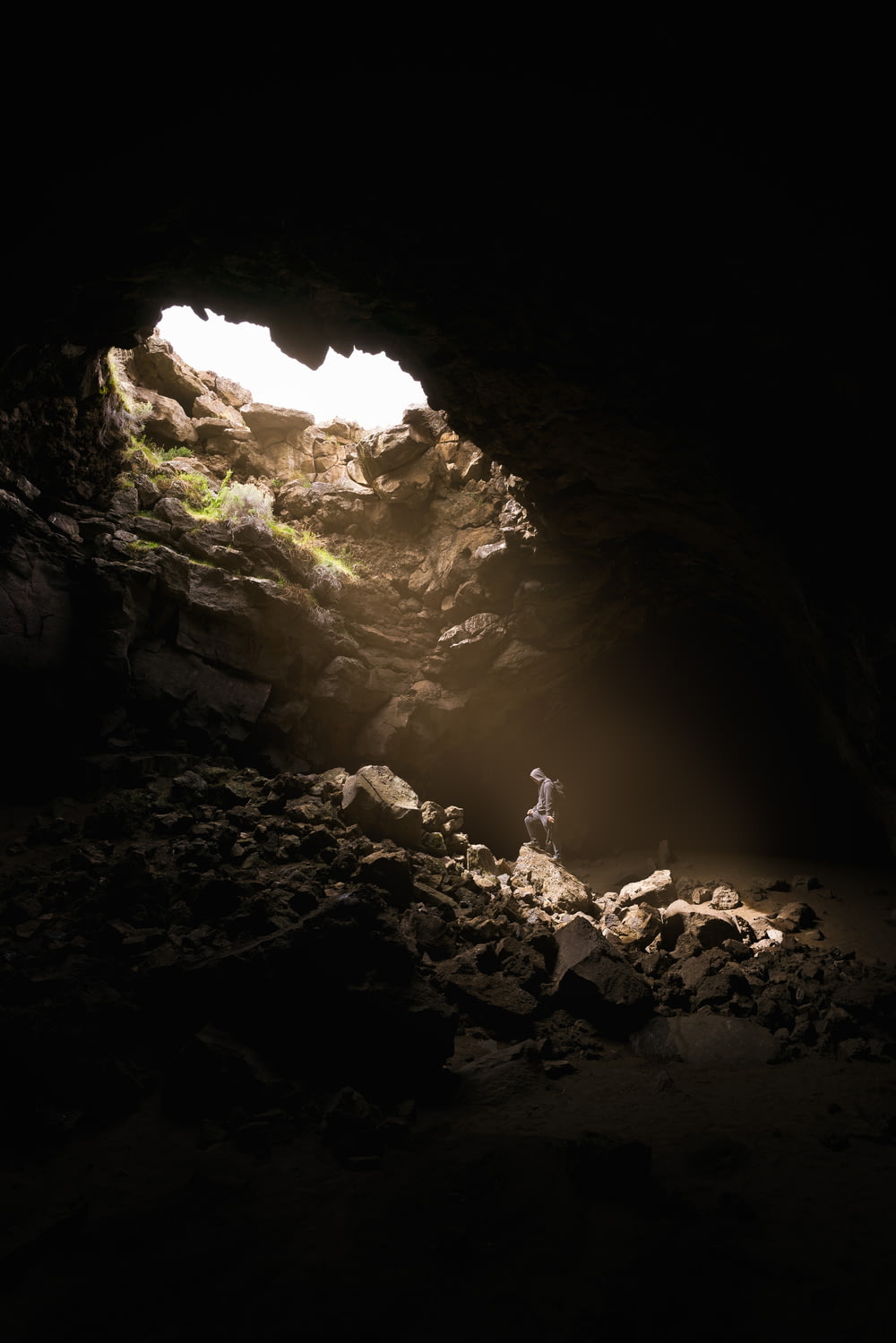 Una persona in piedi in una grotta con una luce che passa attraverso