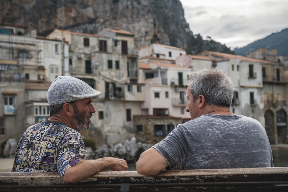 Due uomini seduti sulla panchina che parlano vicino al villaggio durante il giorno