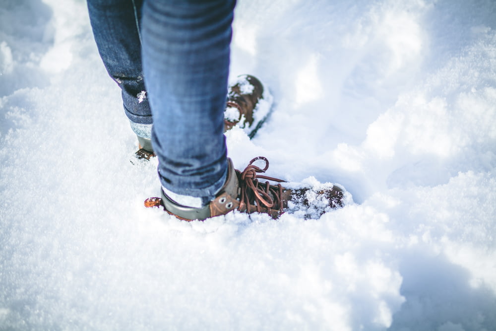 pessoa usando sapatos marrons na neve