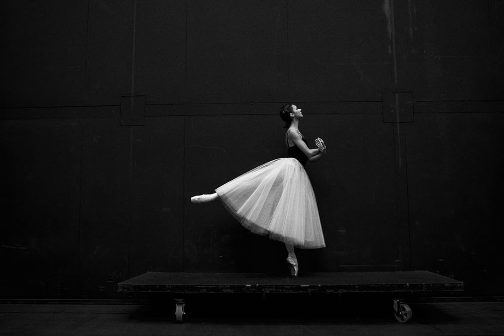 Photographie en niveaux de gris d’une danseuse de ballet debout à bord
