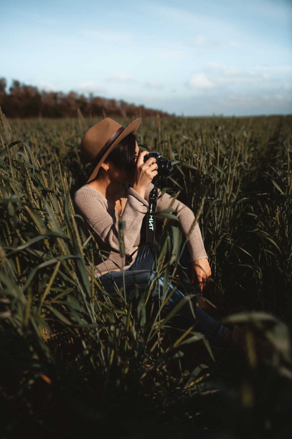 Frau macht Foto, während sie auf grünem Grasfeld sitzt