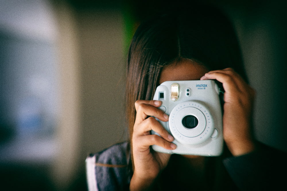 Frau fotografiert mit weißer Fujifilm Instax Mini