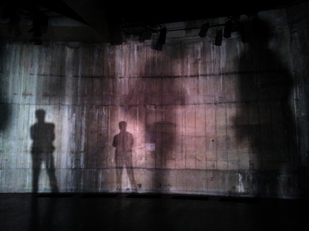 Silhouette eines Mannes, der in der Nähe einer Mauer auf dunklem Bereich steht