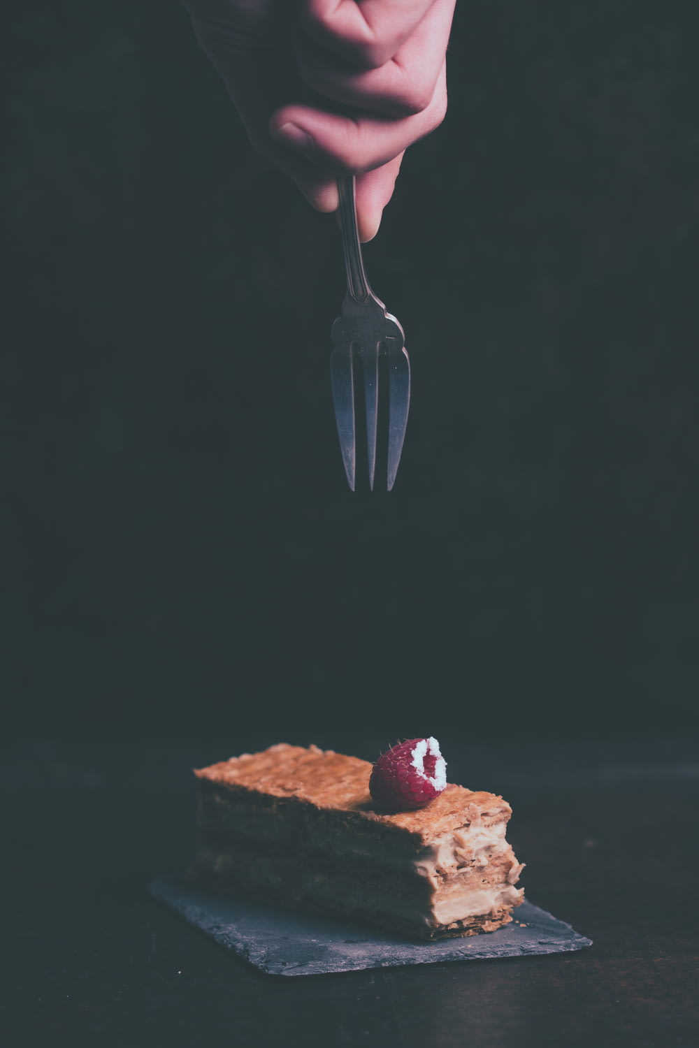 person holding fork about to grab cake