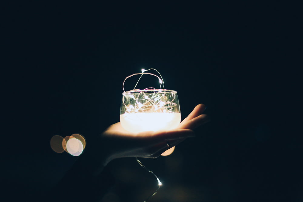 Person mit Kerzenlichthalter aus klarem Glas