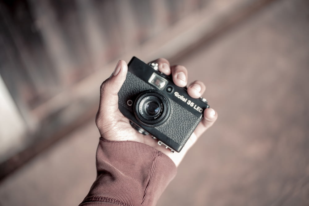 person holding black and gray point-and-shoot camera