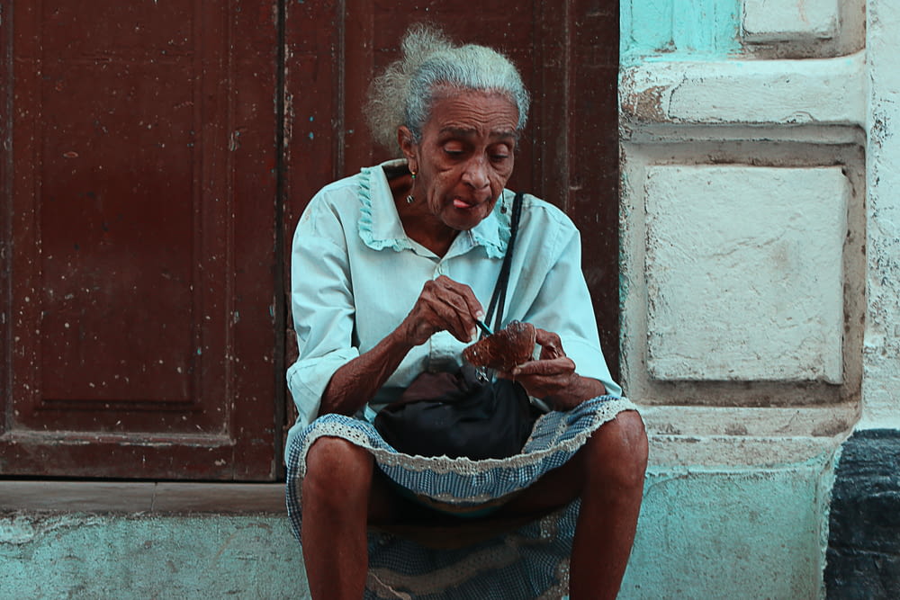 woman sitting on gray concrete ground near brown wooden door
