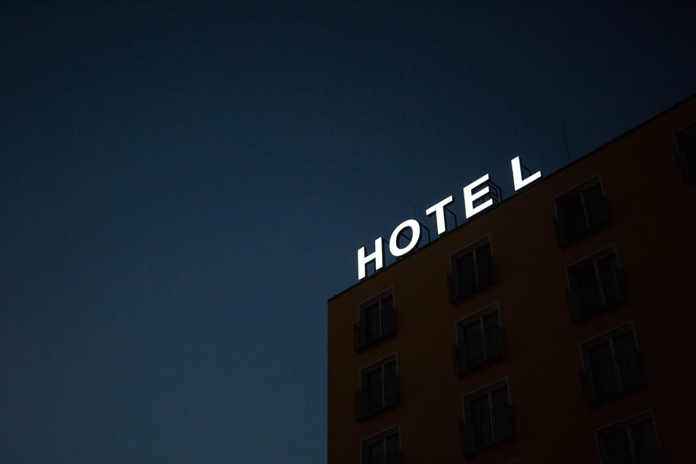 夜間の茶色い建物の屋上にあるホテルの照明付き看板のローアングル写真