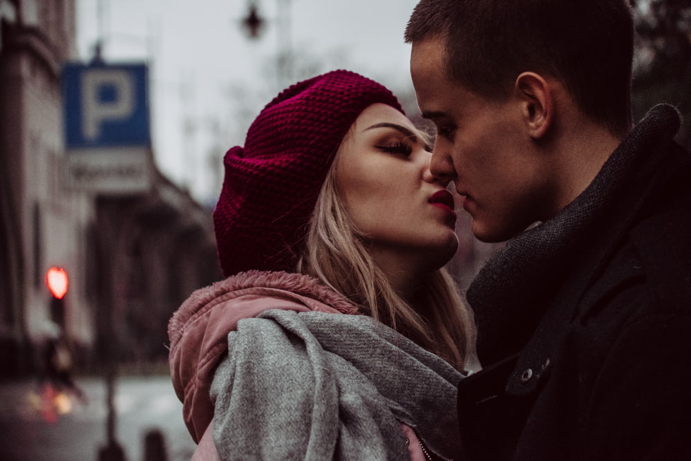 Mann und Frau stehen und küssen sich neben Straßenschildern
