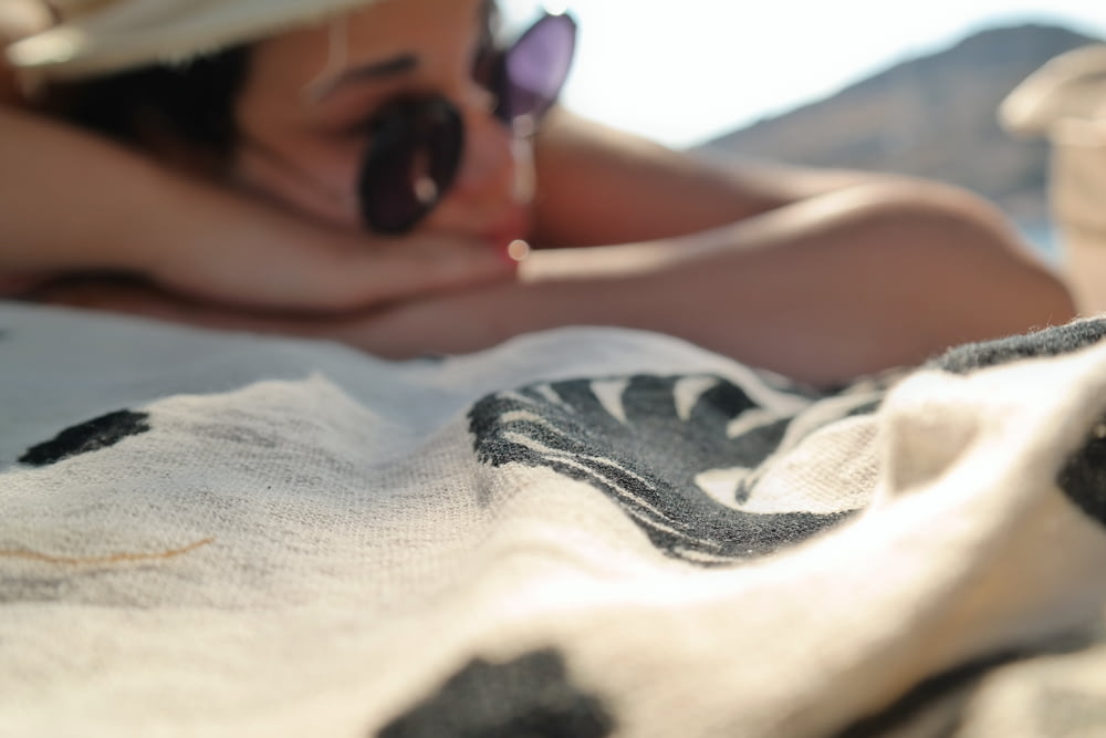 femme couchée sur un textile blanc et noir pendant la journée