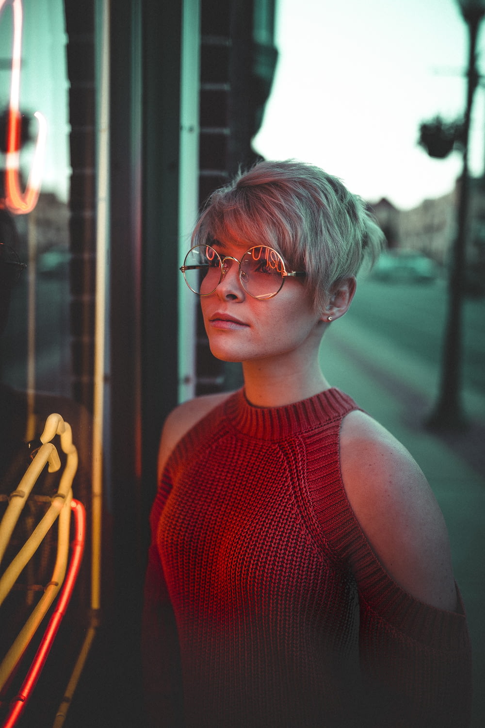 Donna con occhiali che guardano il pannello di vetro con insegne al neon
