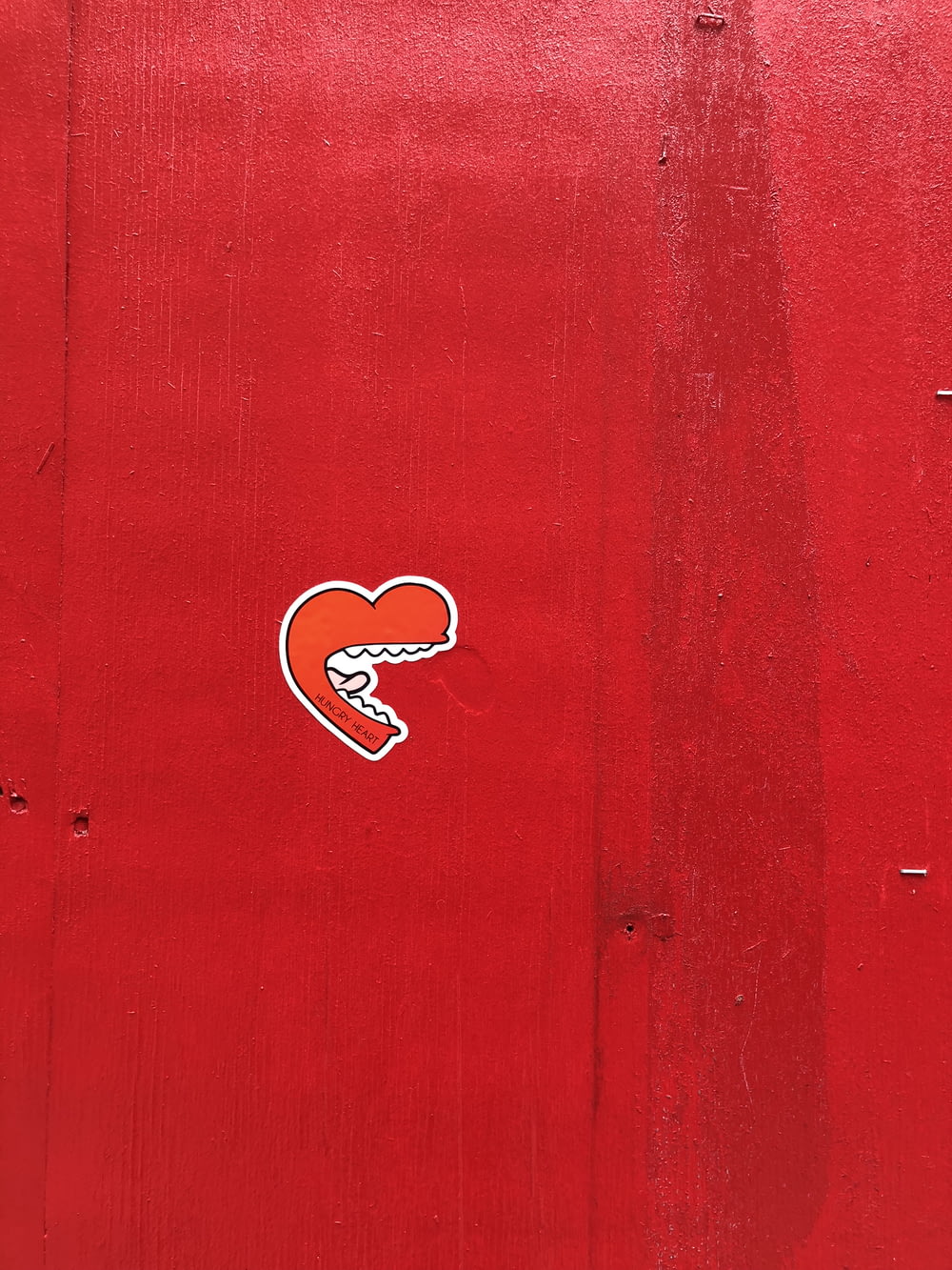 a red wall with a sticker of a heart on it