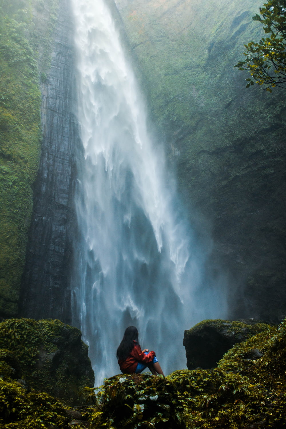 mulher sentada na rocha de frente para cachoeiras de mergulho