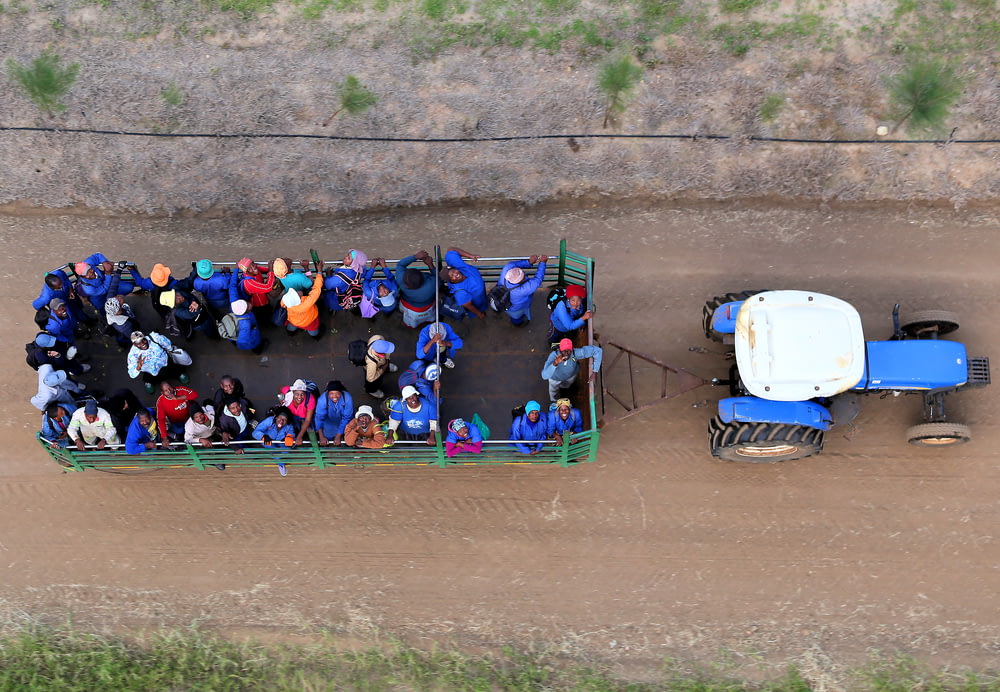 Personnes montant sur un camion transporté par un tracteur bleu dans la photographie de vue de dessus