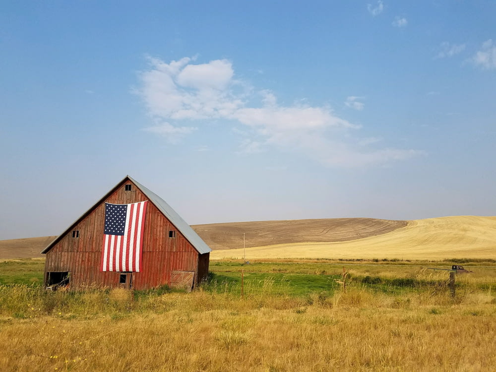 Flagge der Vereinigten Staaten von Amerika tagsüber an braunem Haus aufgehängt