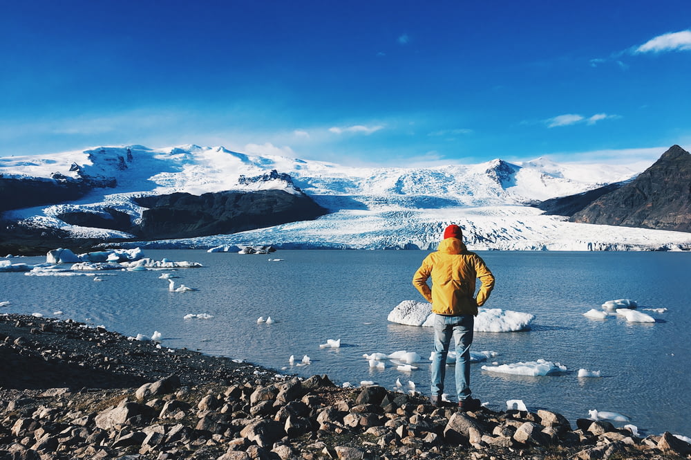 man standing in front of ice lake