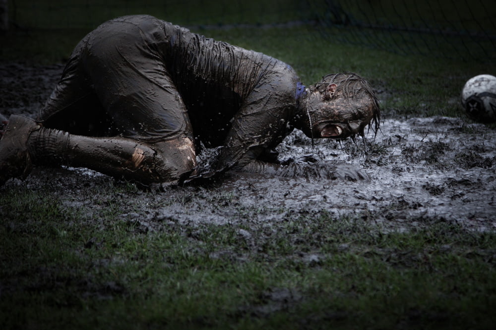 uomo sdraiato sull'erba verde intrisa di fango