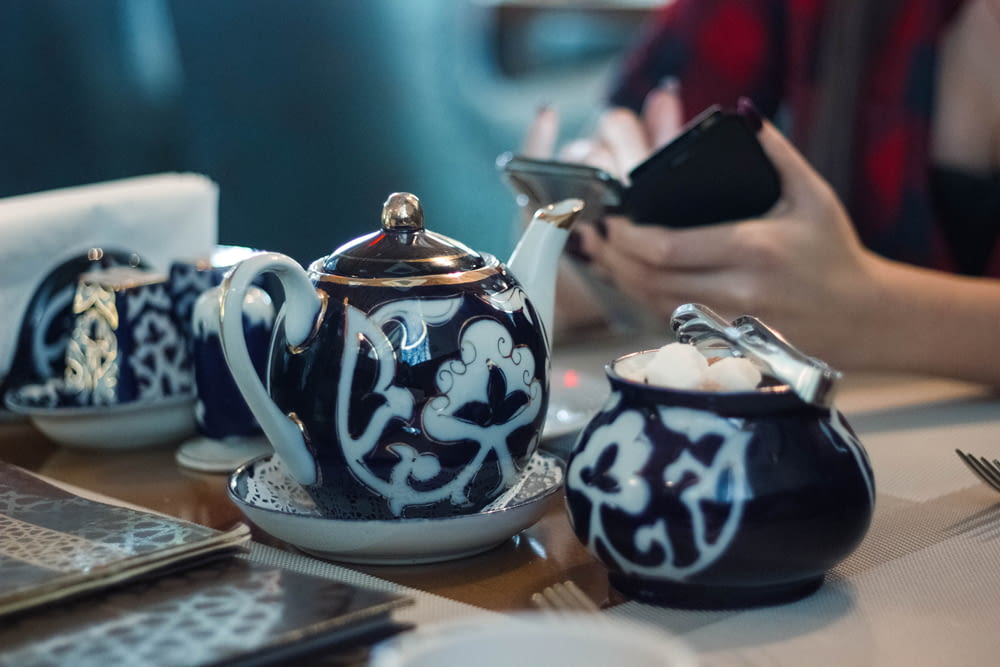 person sitting in front white and black ceramic tea set
