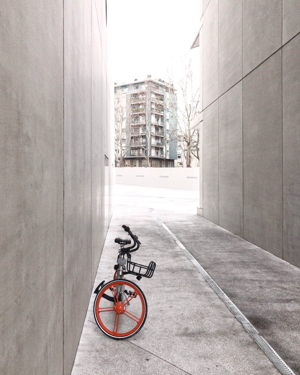 black and orange bicycle in between concrete walls