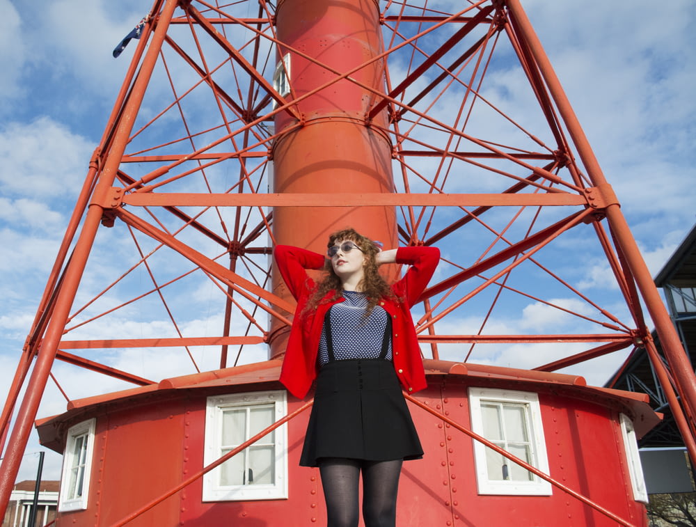 woman standing under red metal tower