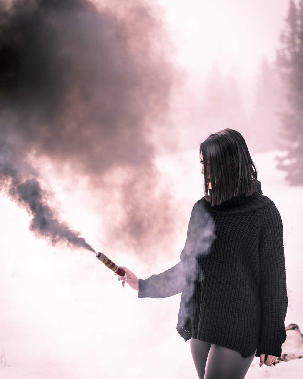 woman in black knit long-sleeved shirt using black stick with smoke