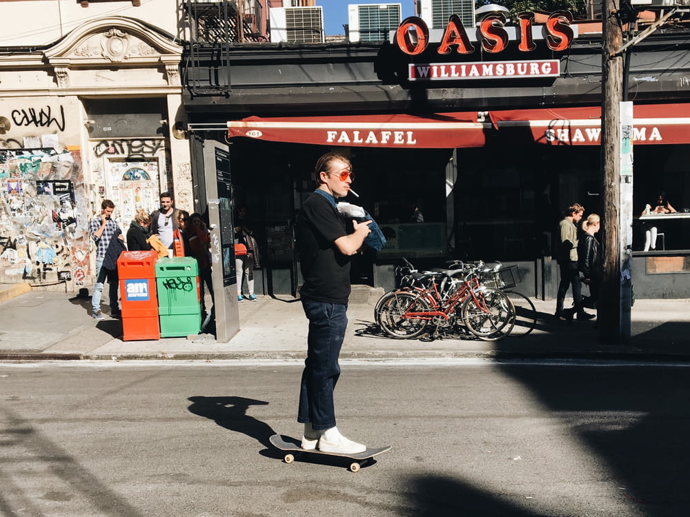 man riding skate near gray and red building during daytime