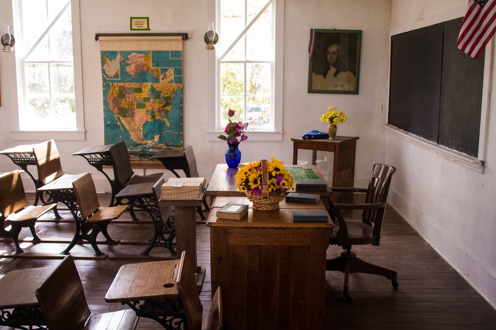 sala de aula pintada de branco vago com cadeiras, mesas e mapa na parede