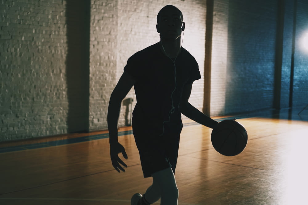 閉鎖されたバスケットボールコートでボールをドリブルする男