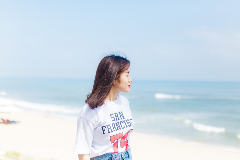 woman in white crew-neck T-shirt walking on seashore