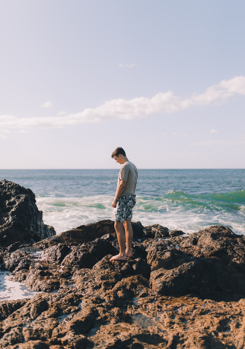 Mann steht auf Felseninsel am Strand