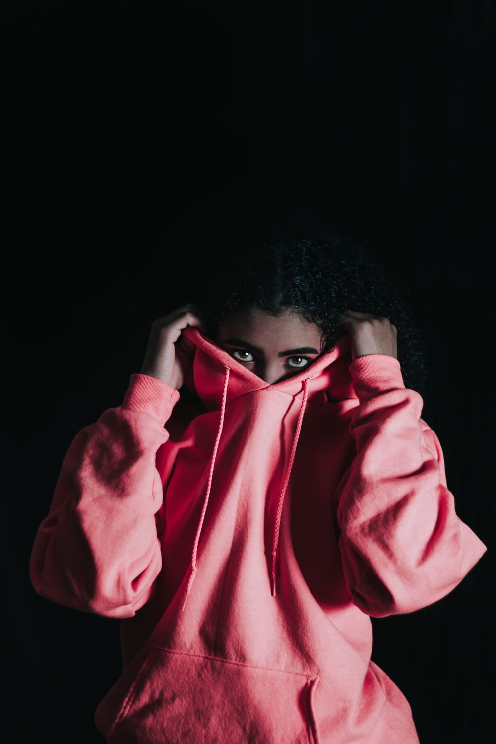Mädchen trägt rosa Pullover-Kapuzenpullover, der ihre Nase bedeckt