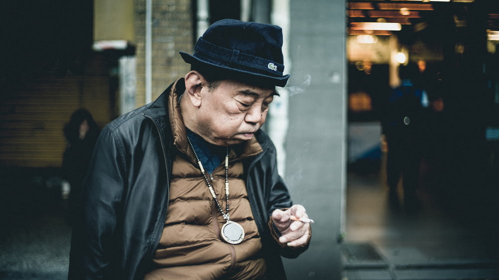 homem na jaqueta de couro preta usando o cigarro
