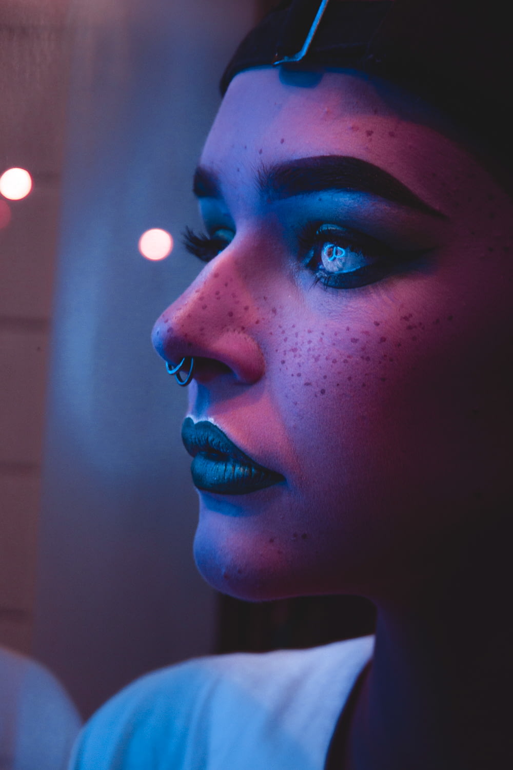 photo of woman with black lipsticks and nose piercings captured inside dim light room